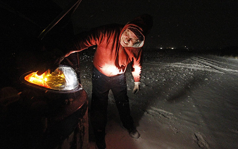 24 hours in pictures: A trucker cleans snow off his headlights in Utah