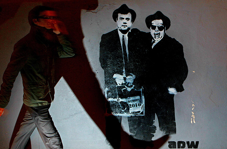 Business Week in Pictures: A pedestrian walks home past graffiti depicting Brian Lenihan Brian Cowen 