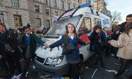 Schoolgirls join hands to peacefully stop attacks on a police van during student protests in London.