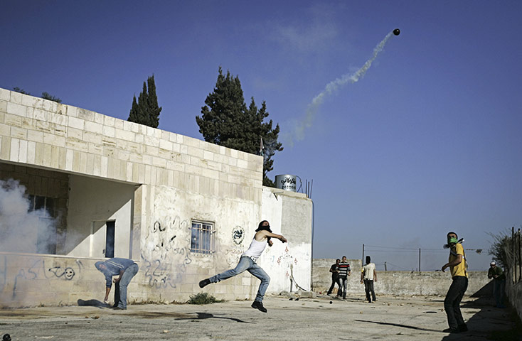 24 hours in pictures: A masked Palestinian protester throws tear gas
