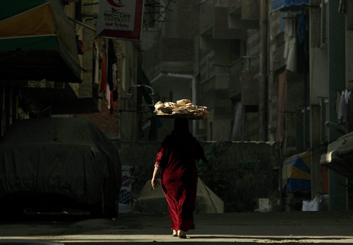 24 hours in pictures: A woman carries bread on top of her head in Alexandria