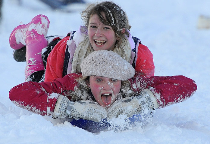 Snow and freezing hits uk: Rachel Douglass and Sophie Coatsworth sledge downhill 