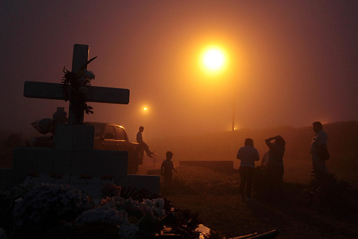 24hours in pics: People stand under lamp lights in a cemetery on Day of the Dead 