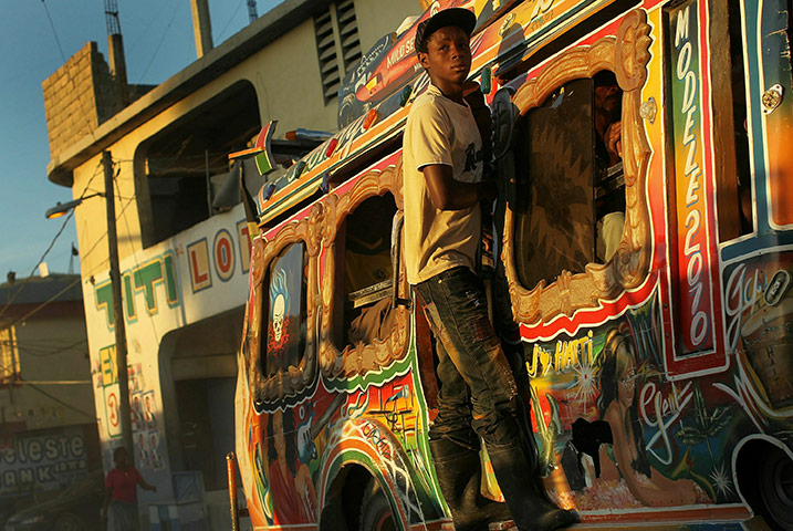 24hours in pics: Port au Prince, Haiti: A teenager hangs onto a bus 