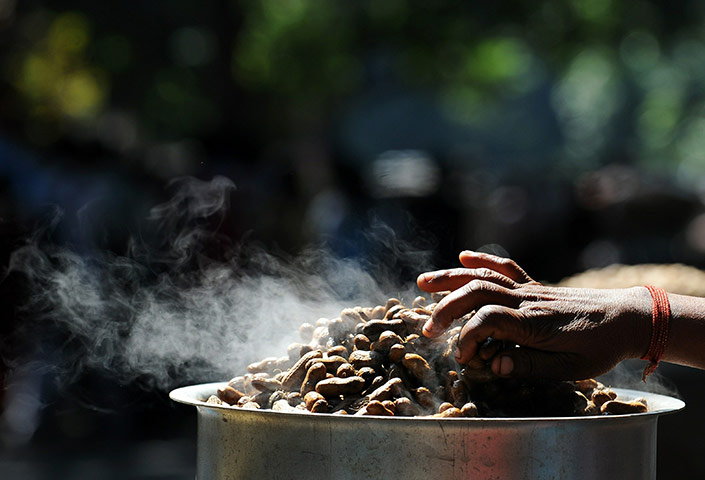24 hours in pictures: An Indian groundnut vendor waits for customers