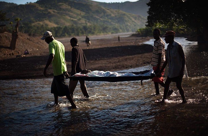 24 hours in pictures: Cholera sufferer is carried on a stretcher by relatives, Haiti