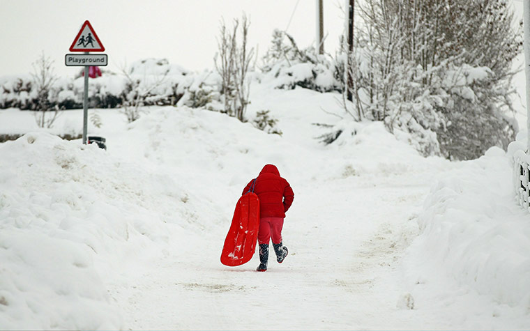 More Snow hits the UK: A girl walks up a hill with a sledge in Dunning