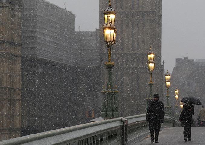 More Snow hits the UK: Pedestrians walk across Westminster Bridge as snow falls, in London