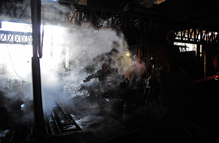 From the agencies: A steel worker is pictured as he cools machinery with water