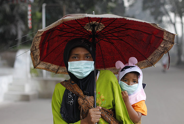 Mount Merapi Update: A mother carries her child in the city of Muntilan