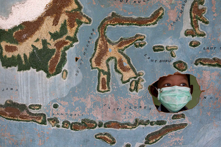 Mount Merapi Update: A student plays behind a map of Indonesia Candi Binangun village in Sleman