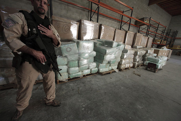 Tunnel Drug Smuggling: Agent from ICE stands guard in front of blocks of marijuana in Otay Mesa