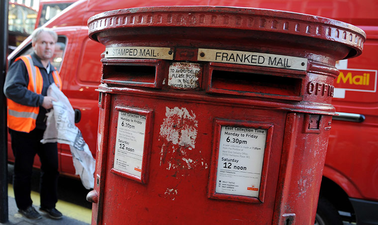 Week In Business:  A Royal Mail worker collects mail from a post box in London