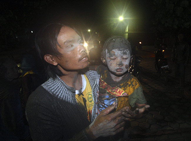 Merapi Volcano Update: A man carry his boy flee their home following another eruption Mount Merapi