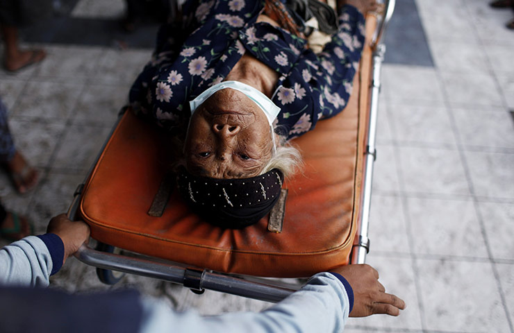 24 Hours: A volunteer pushes an elderly woman at a temporary shelter in Indonesia