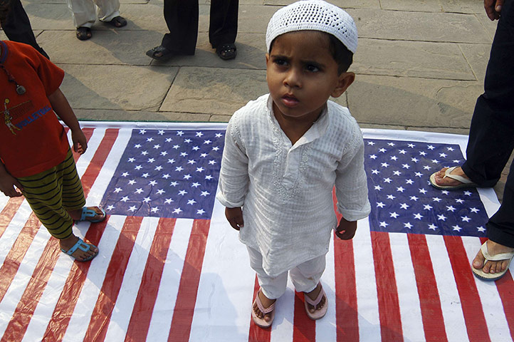 Obama Visit to Asia: A Shi'ite Muslim boy stands on a U.S. flag during a protest in Lucknow