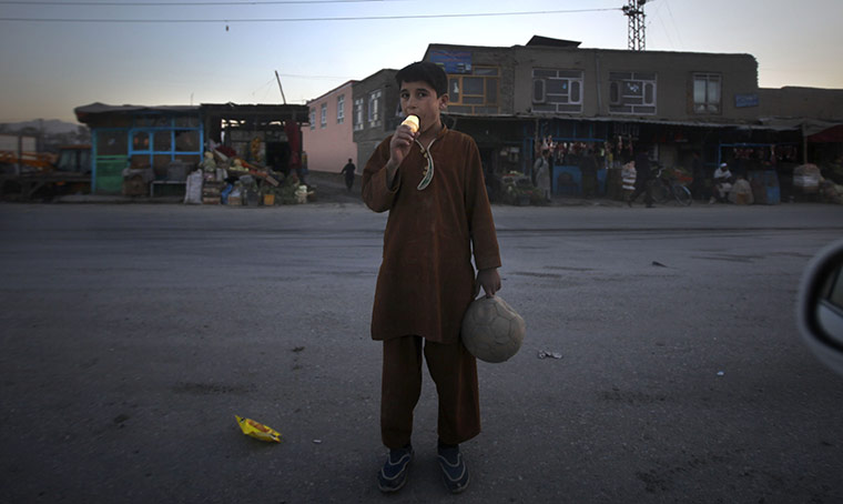 24 hours: An Afghan boy licks an ice cream as he waits to cross a road