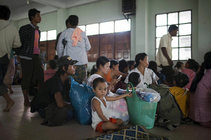 Burma refugees: A young refugee sits with his family and belongings in a temporary shelter