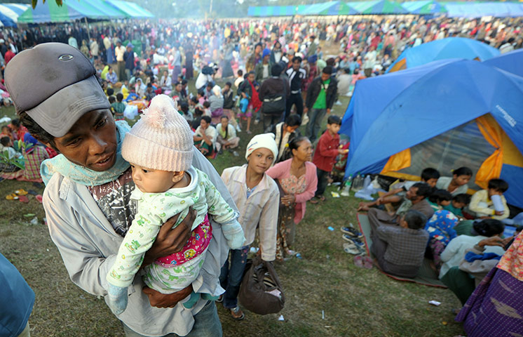 Burma refugees: A man carries his child as refugees arrived in a temporary camp