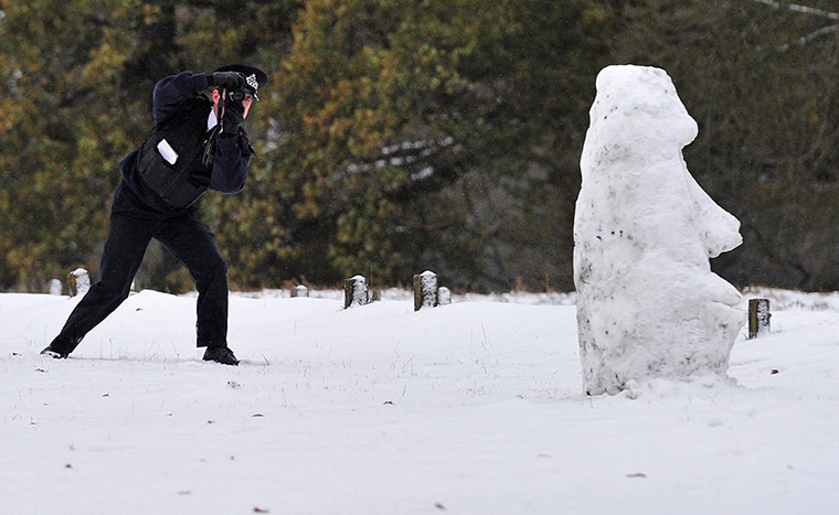 Snow today: A Parks Police officer takes photographs of a snowman in Richmond Park