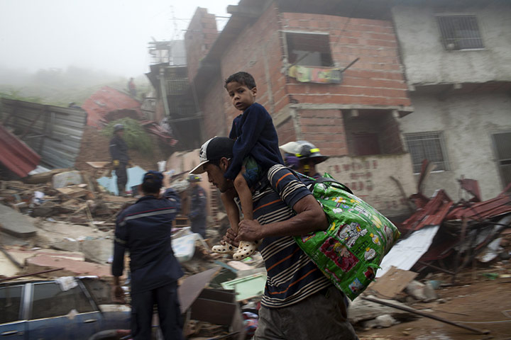 Venezuela floods: A man and his son carry their belongings as they evacuate