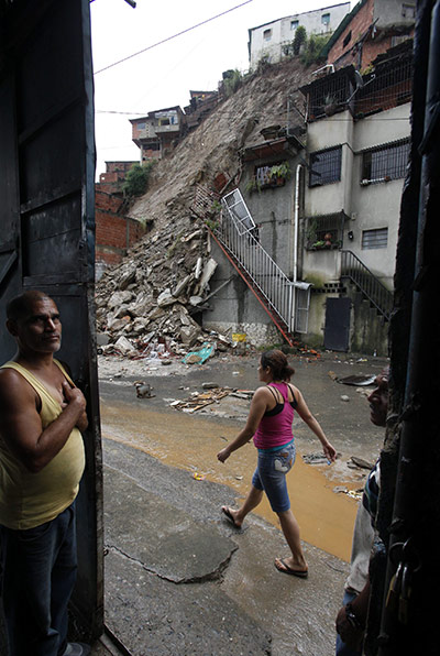 Venezuela floods: A woman walks next to debris from a landslides due to heavy rain in Caracas