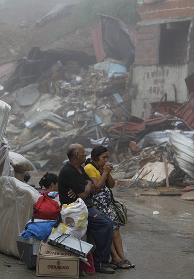 Venezuela floods: People sit with their belongings as they evacuate from their home
