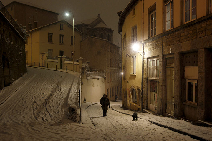 24 hours in pictures: A woman walks with her dog as snow falls in Lyon
