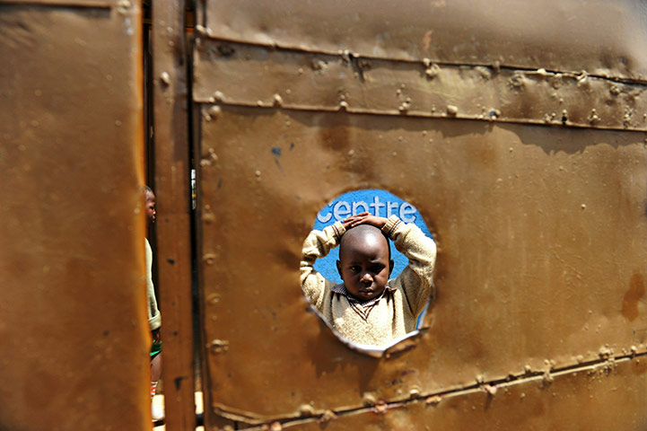 24 hours in pictures: Child stands in the inside courtyard of the preschool he attends in Kibera