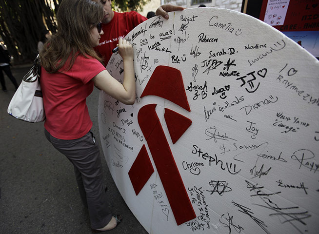 AIDS World day: A girl signs a board next to a red ribbon to commemorate World Aids Day 