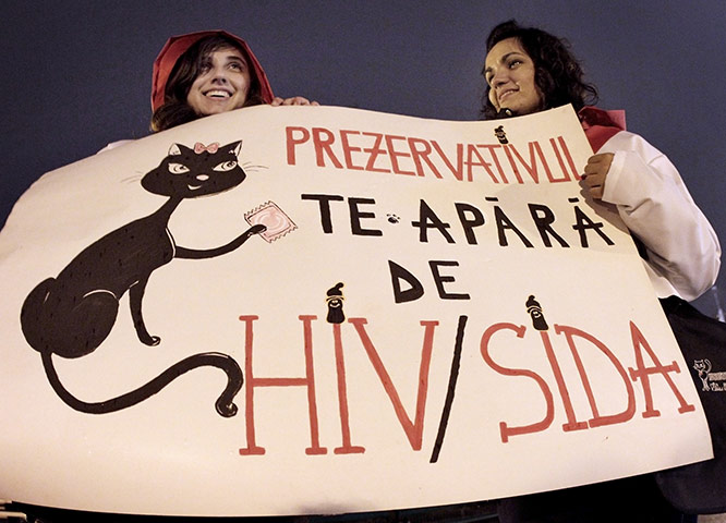 AIDS World day: Girls hold a banner that reads Condoms protect you of HIV/AIDS
