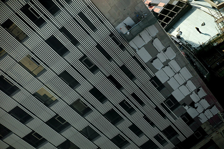 24 hours in pictures: Shanghai, China: A Chinese worker is dwarfed by a high rise building