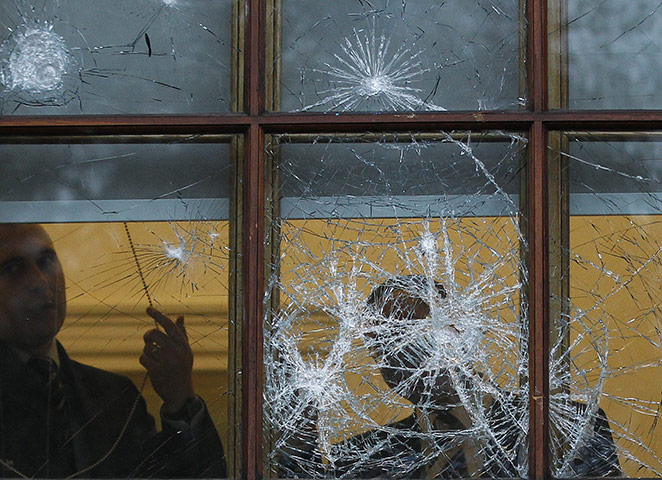 Student Protest Aftermath: People stand behind a damaged Treasury building window