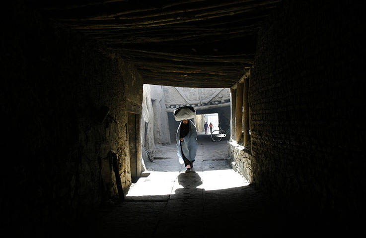 24 Hours in Pictures: An Afghan woman walks towards a market in the old city of Kabul Afghanistan