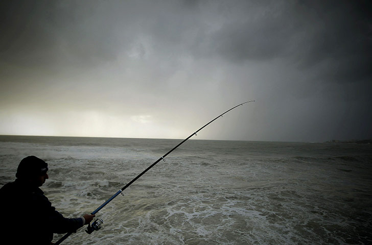 24 Hours in Pictures: A man fishes during a storm on the Mediterranean coast of Byblos, Lebanon