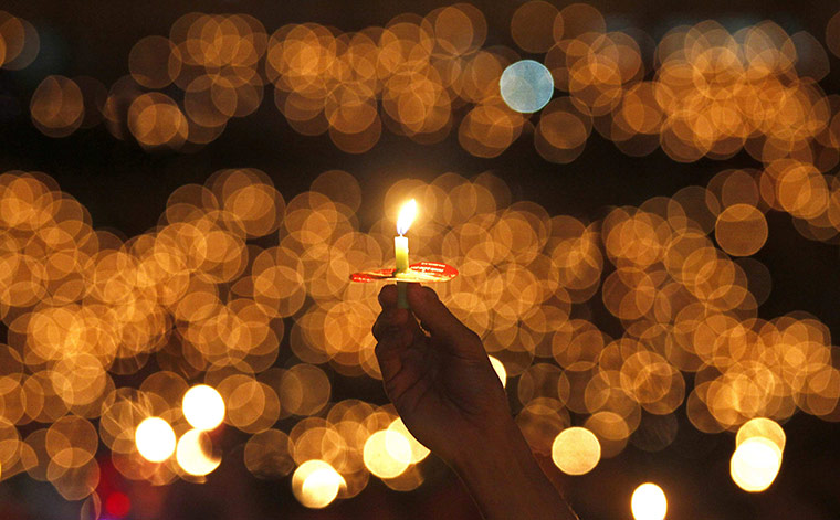 24 Hours in Pictures: A man hold a candle during a Christmas mass at Gelora Bung Karno stadium