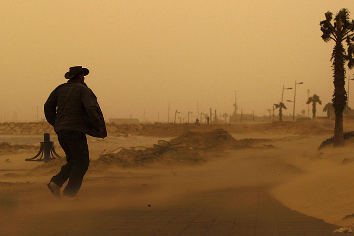 24 hours: Ashkelon, Israel: A man walks on a beach during a dust storm