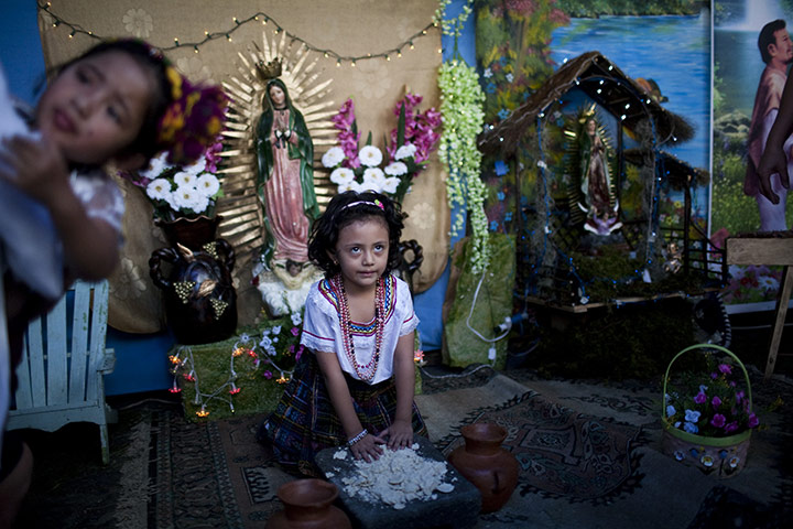Guadalupe festival : A girl poses for a photograph with images of the Virgin of Guadalupe 