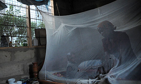 A mother and child sit under a mosquito net in Tanzania