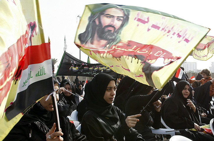 Ashura Religious Festival: Iraqi Shiite women wave flags with a picture of Imam Hussein