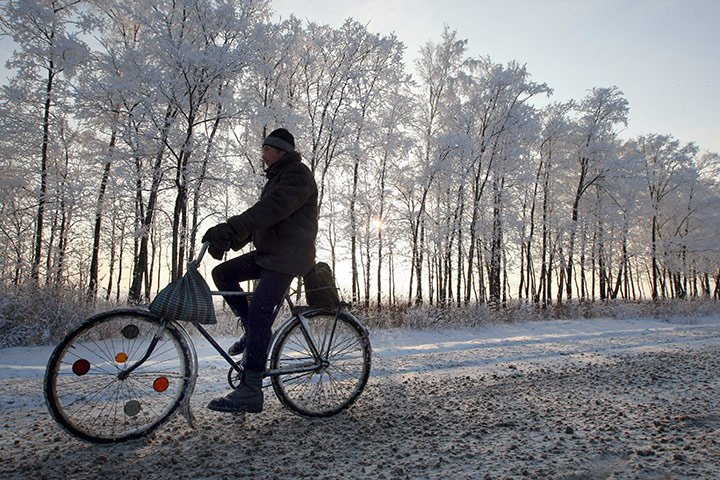 Winter Weather Europe: A man rides his bike on a snow-covered r