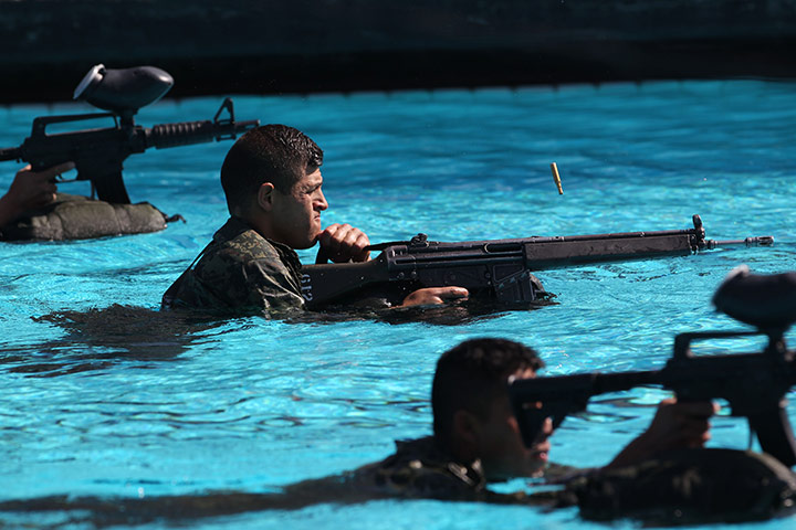 24 hours in pictures: An army cadet fires a weapon from a swimming pool in combat training course