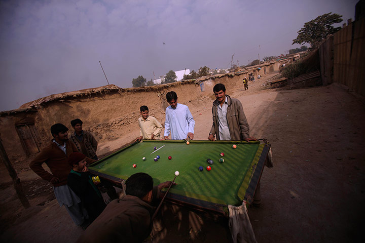 24 hours in pictures: Afghan men play pool in a slum area on the outskirts of Islamabad