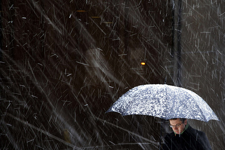 Winter Weather in the UK: A man with an umbrella walks during a snowfall in London