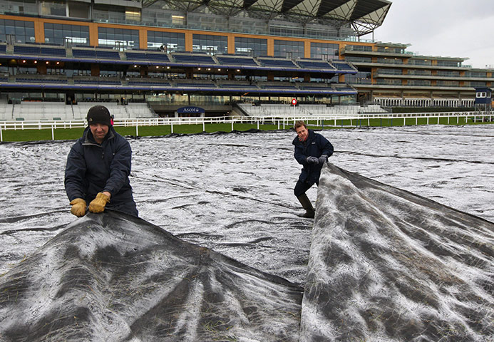 Winter Weather in the UK: Clerk of The Course Chris Stickels and a groundsman remove a frost cover
