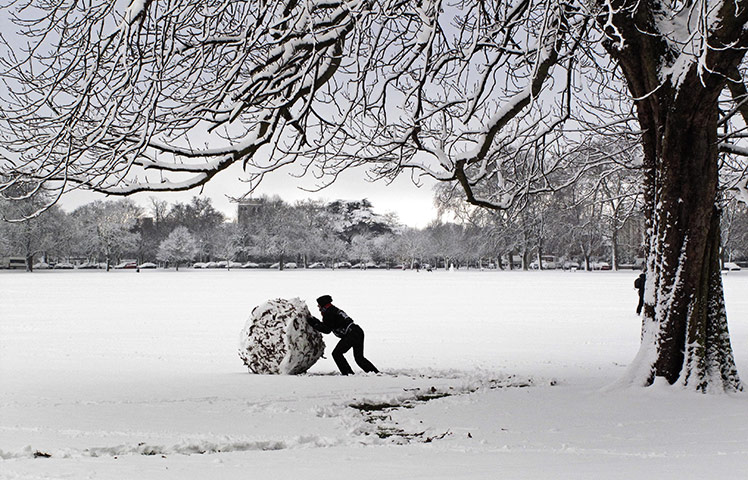 Snow: man pushes a giant snow ball