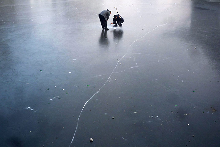 24 hours: Beijing, China: Fishermen use a stick and a rock to make a hole in the ice
