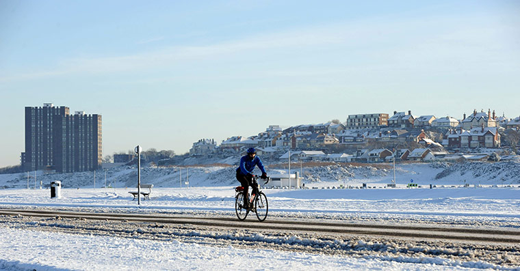 Cold weather continues: A man cycles along a snow-covered road in New Brighton near Liverpool
