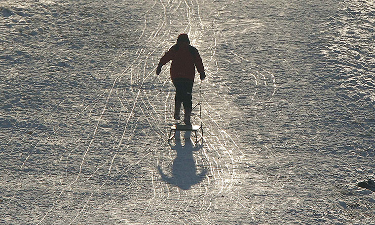 Cold weather continues: A boy pulls his sledge back up a hill at Dunham Massey park in Cheshire