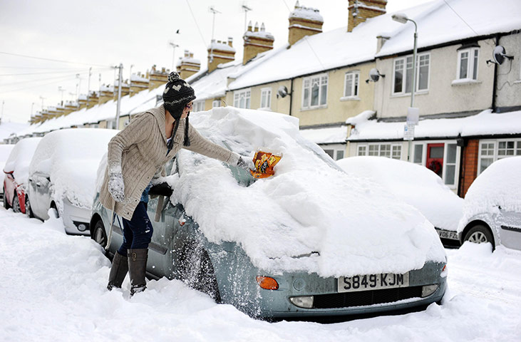Cold weather continues: A woman clears deep snow from her car on a street in Cirencester, Wiltshire